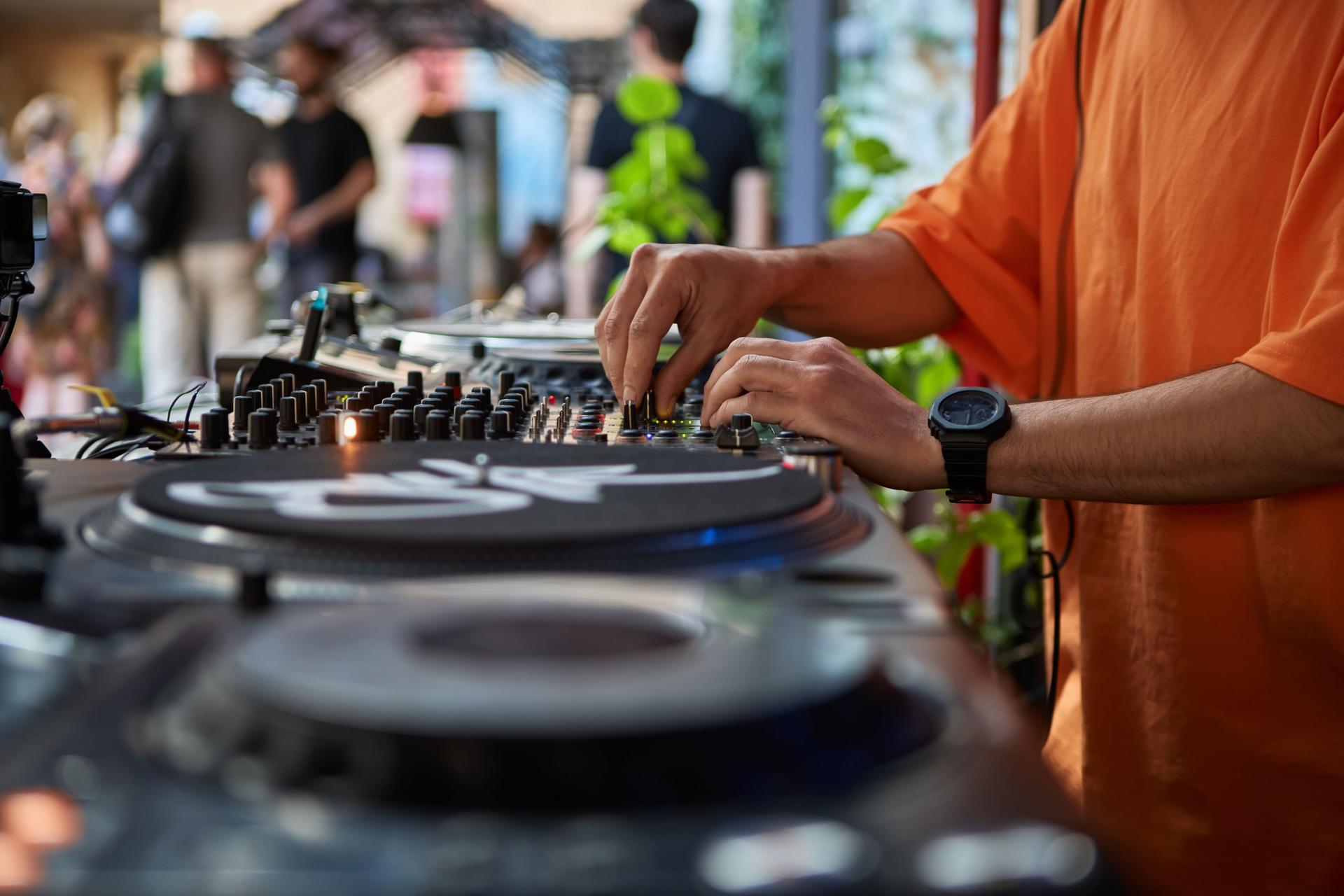 Hip hop DJ playing music on a summer festival. Hands of a club disc jockey mixing musical tracks on a party. Male disk jokey plays set on a entertainment event in a bar